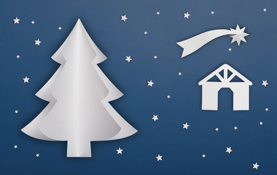 Na ciemnoniebieskim tle wycięte z białego papieru elementy. Po lewej stronie choinka, po prawej szopka a nad nią betlejemska gwiazda - kometa. Dookoła drobne gwiazdki.